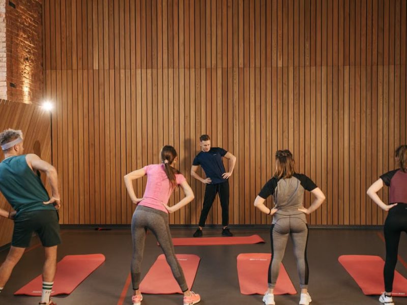 People stretching on yoga mats during a fitness class indoors.