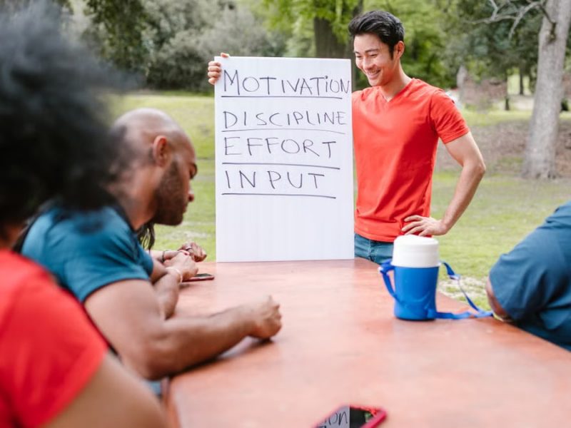 A diverse group of adults engaged in a motivational team building session outdoors.