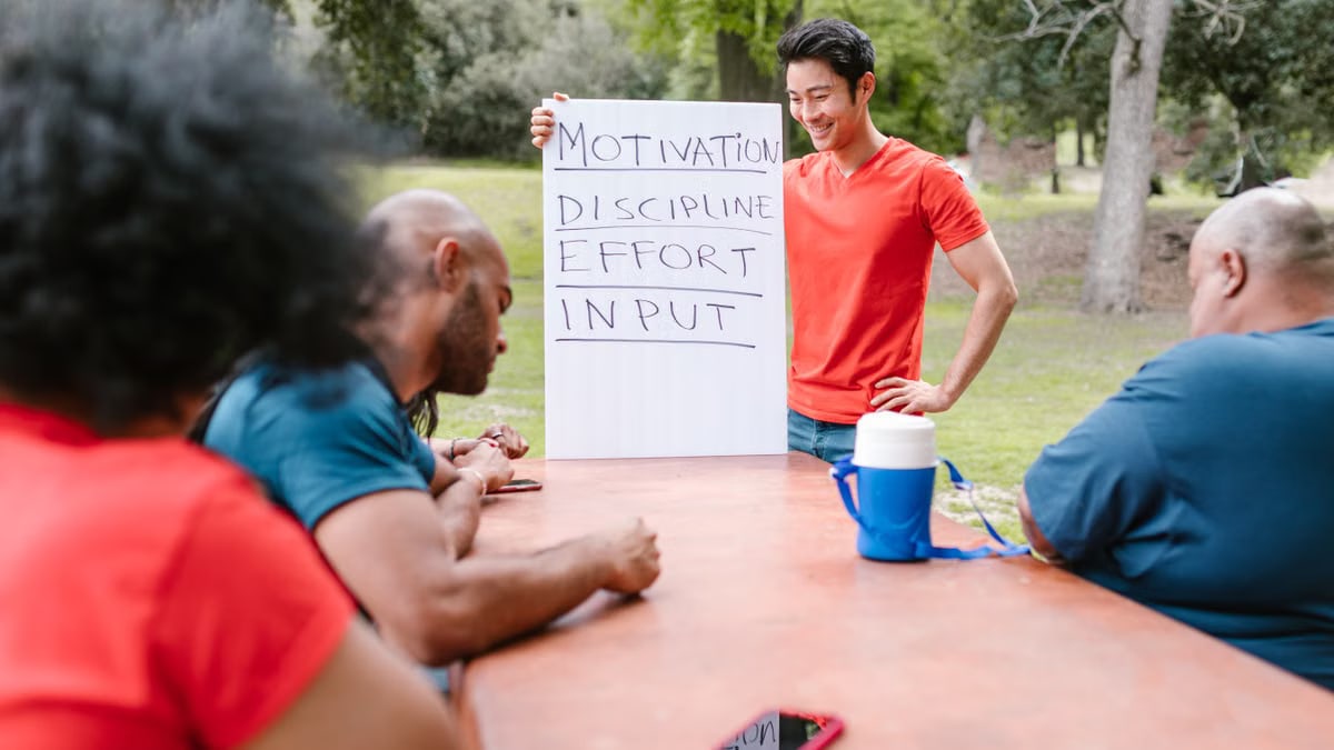 A diverse group of adults engaged in a motivational team building session outdoors.